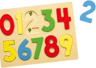 A wooden tray puzzle with the digits nought to nine cut into it as coloured pegged pieces, the number two lifted out and set beside it.