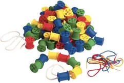 A heap of plastic cotton reels in red, blue, green and yellow with coloured threading laces beside them.