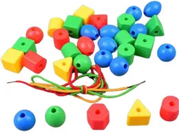 Large plastic beads in red, yellow, green and blue -- cubes, cones, spheres and triangles -- with laces beside them.