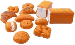 Plastic play bread laid out on white: croissants, a plaited loaf, round buns, a long roll, a doughnut and two sliced loaves.