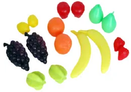 Plastic play fruit laid out on white: two bunches of dark grapes, lemons, red tomatoes, oranges, two bananas, green pears, a red pepper and two limes.