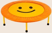 A small round trampoline with an orange padded edge, a yellow mat printed with a smiling face, and yellow legs.