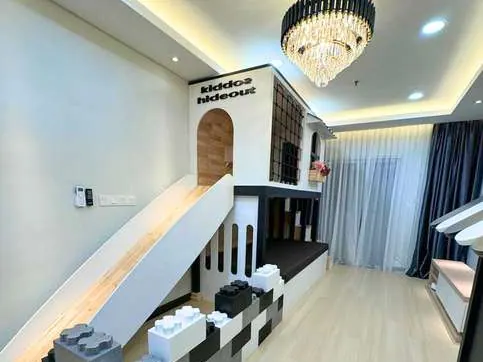 Apartment living room with a white slide from a mezzanine, giant black and white foam blocks, and a crystal chandelier.