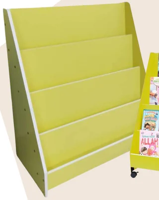 An apple-green sloped book shelf with four display tiers; a second unit of the same shelf, holding books, stands at the edge of the frame.