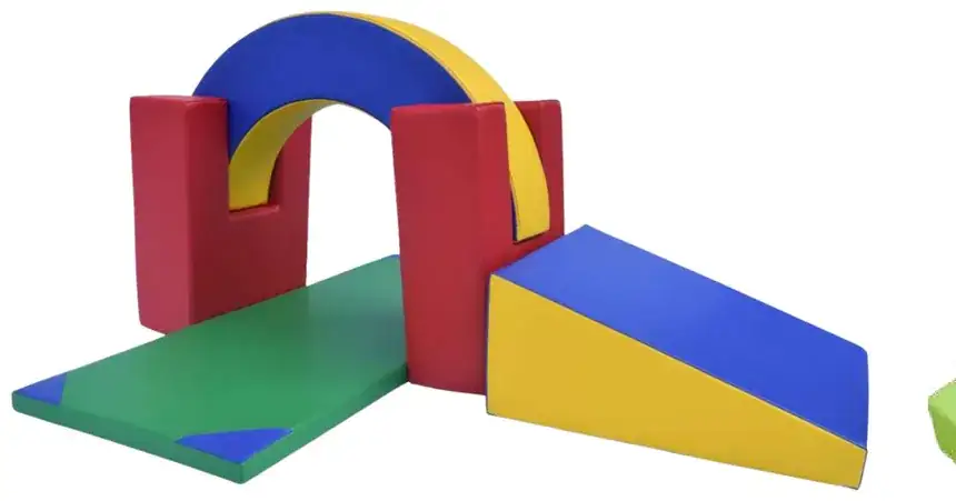A red and yellow arch over a green mat, with a blue and yellow wedge slide beside it.